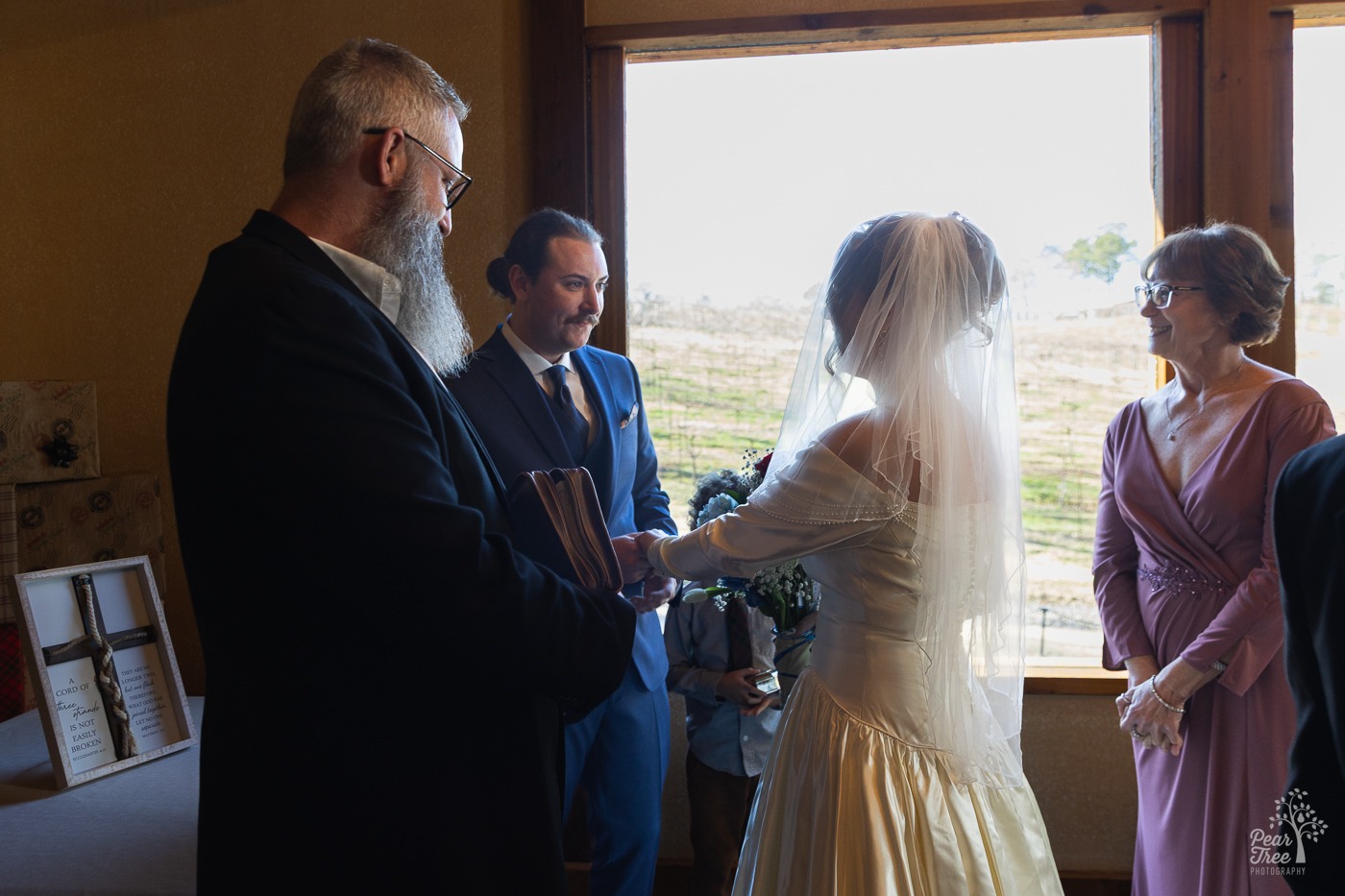 Bride approaching groom and holding his hands with a smiling mom in the background at a Big Door Vineyard wedding ceremony