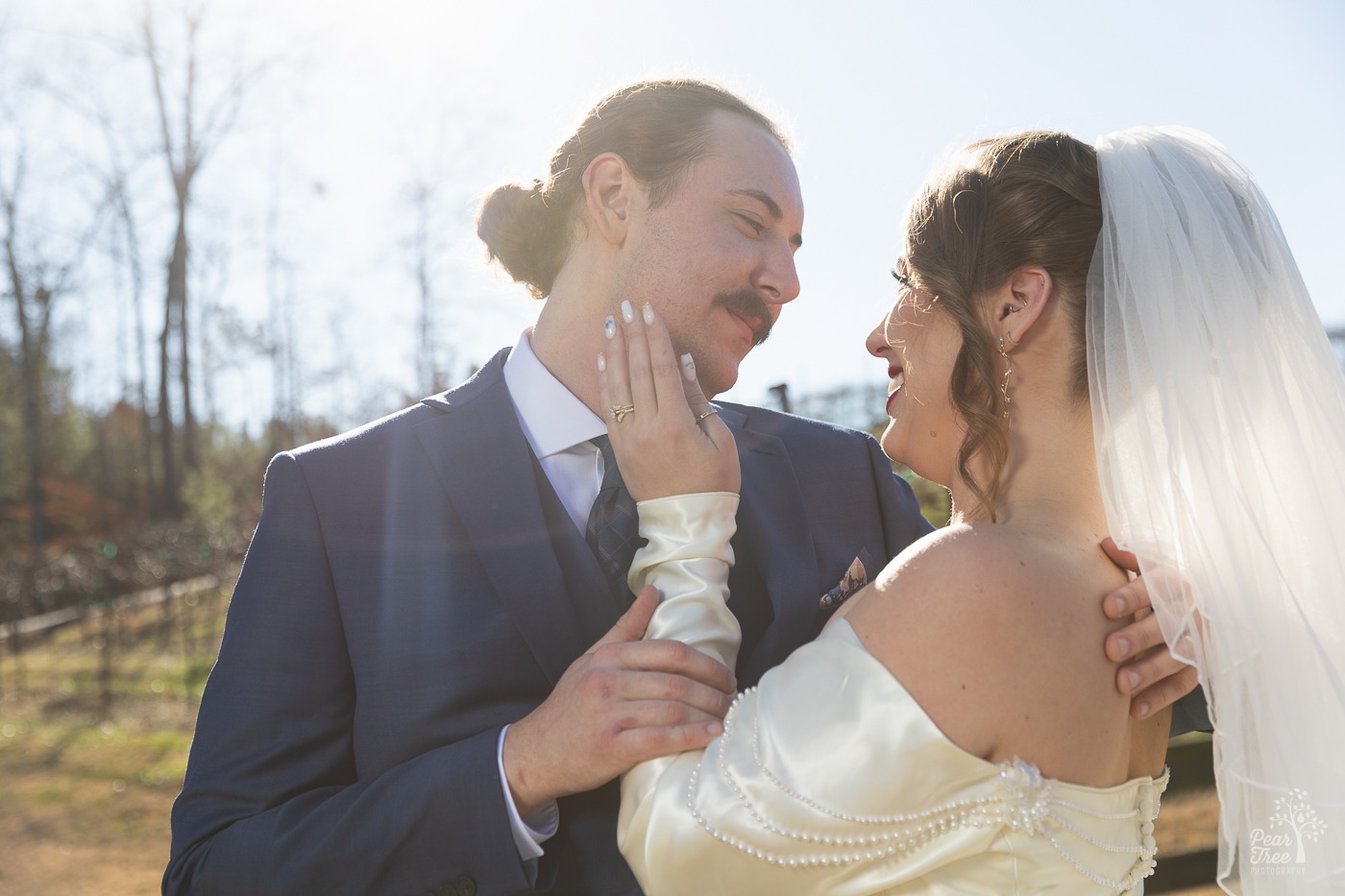 Smiling bride and groom standing close and touching each other sweetly