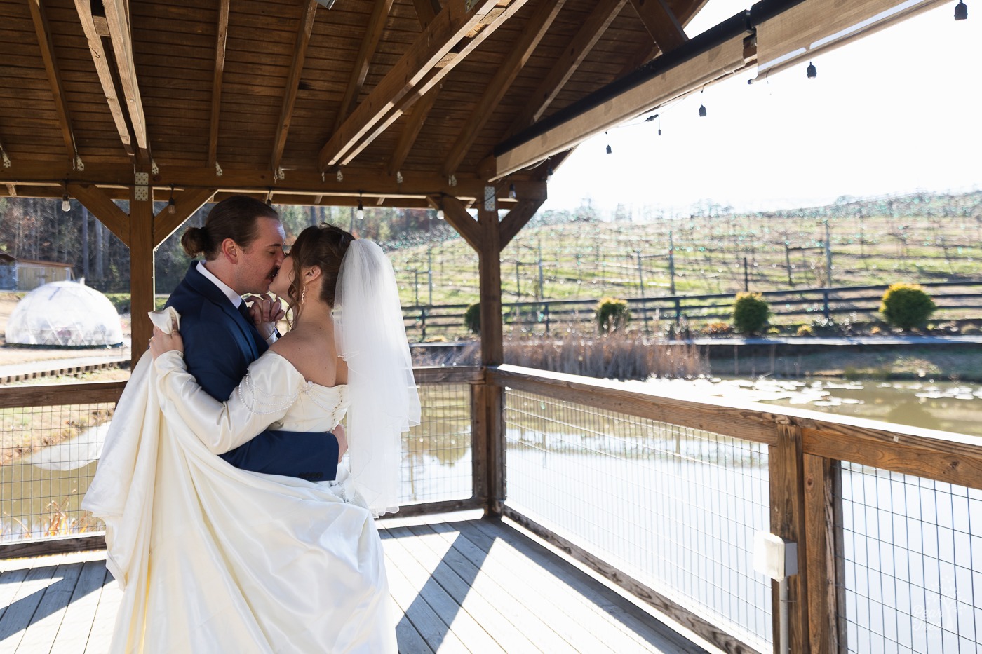 Bride and groom kissing during first dance with Big Door Vineyards vines in background