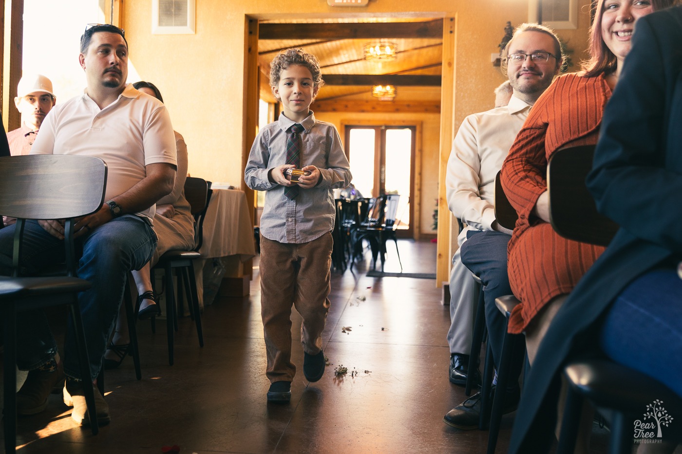 Little boy carrying a ring box down the aisle before a wedding starts