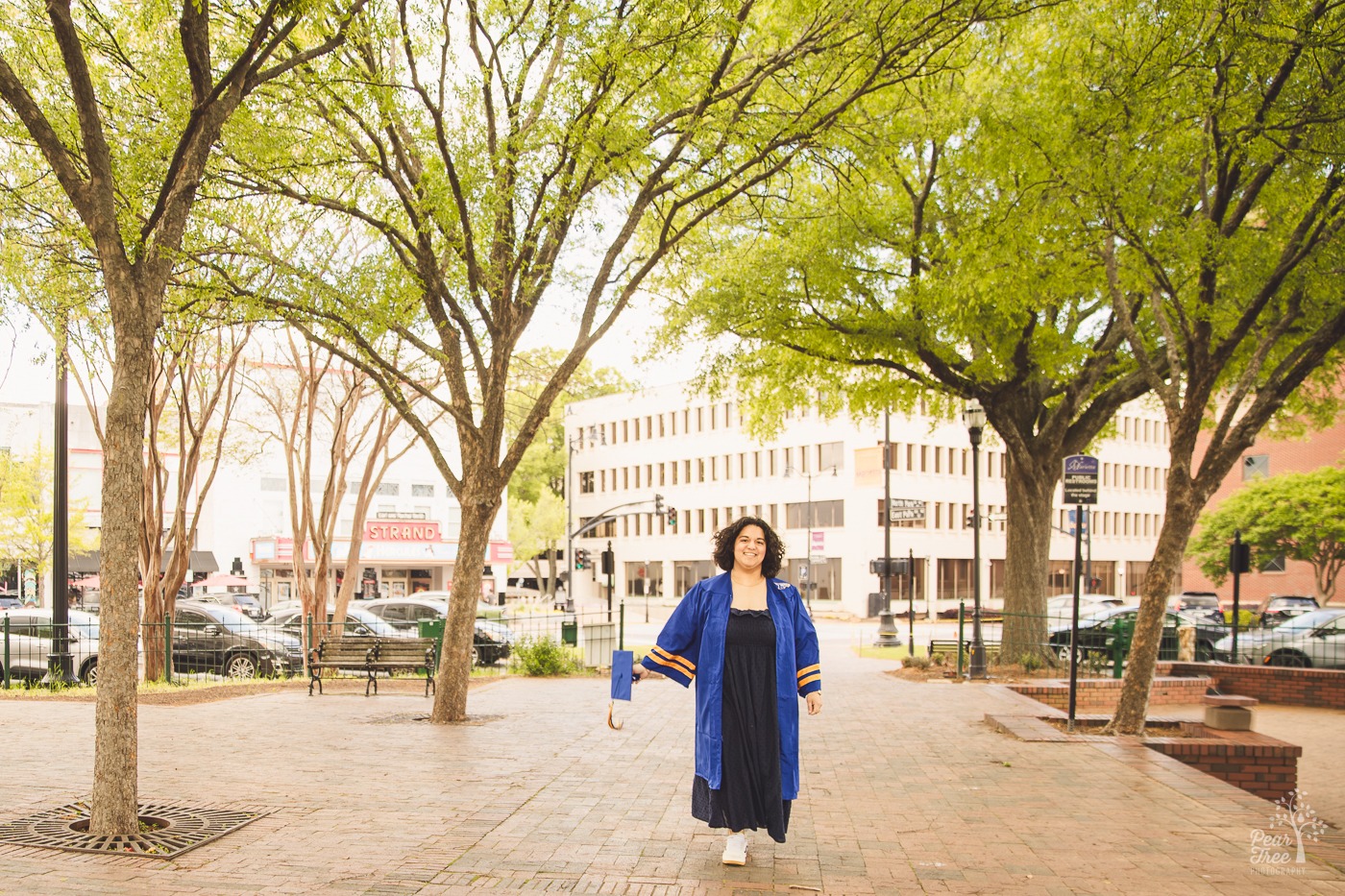 Etowah high school senior wearing her blue gown and holding her cap out in the middle of Marietta Square