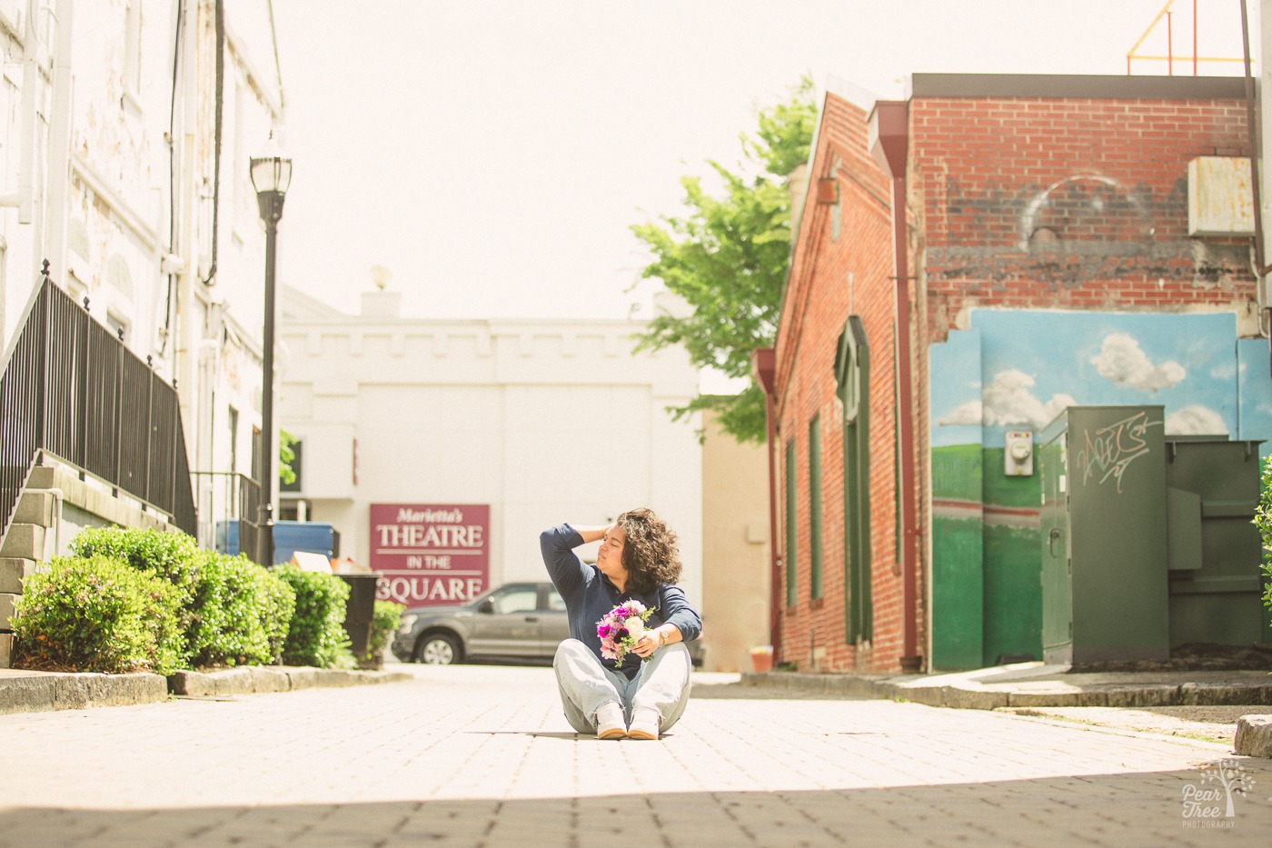 Teenage girl sitting in an alley moving hair out of her face