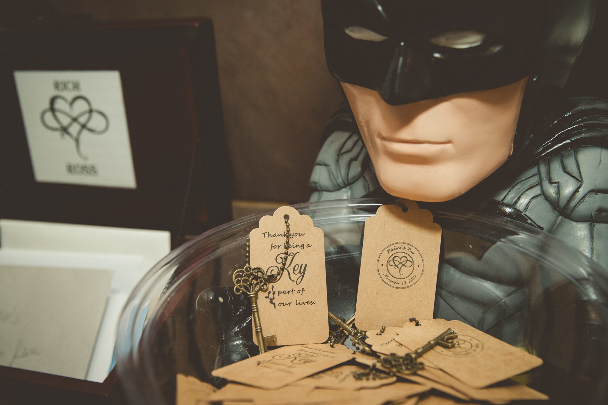 A large Batman figurine holding a glass bowl filled with keys and notes saying, "Thank you for being a Key part of our lives.