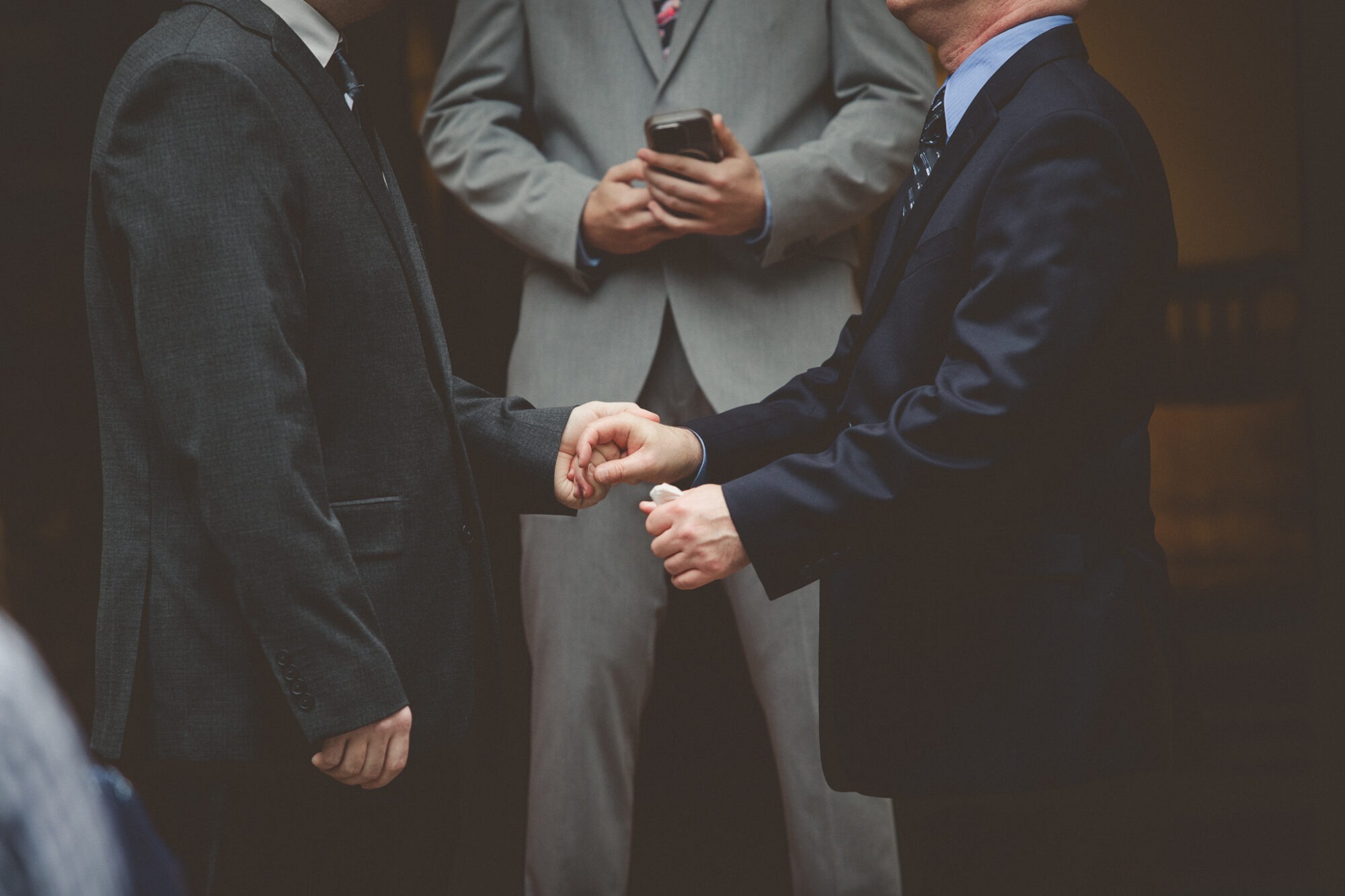 Torso view of two grooms holding hands in the middle of their wedding ceremony