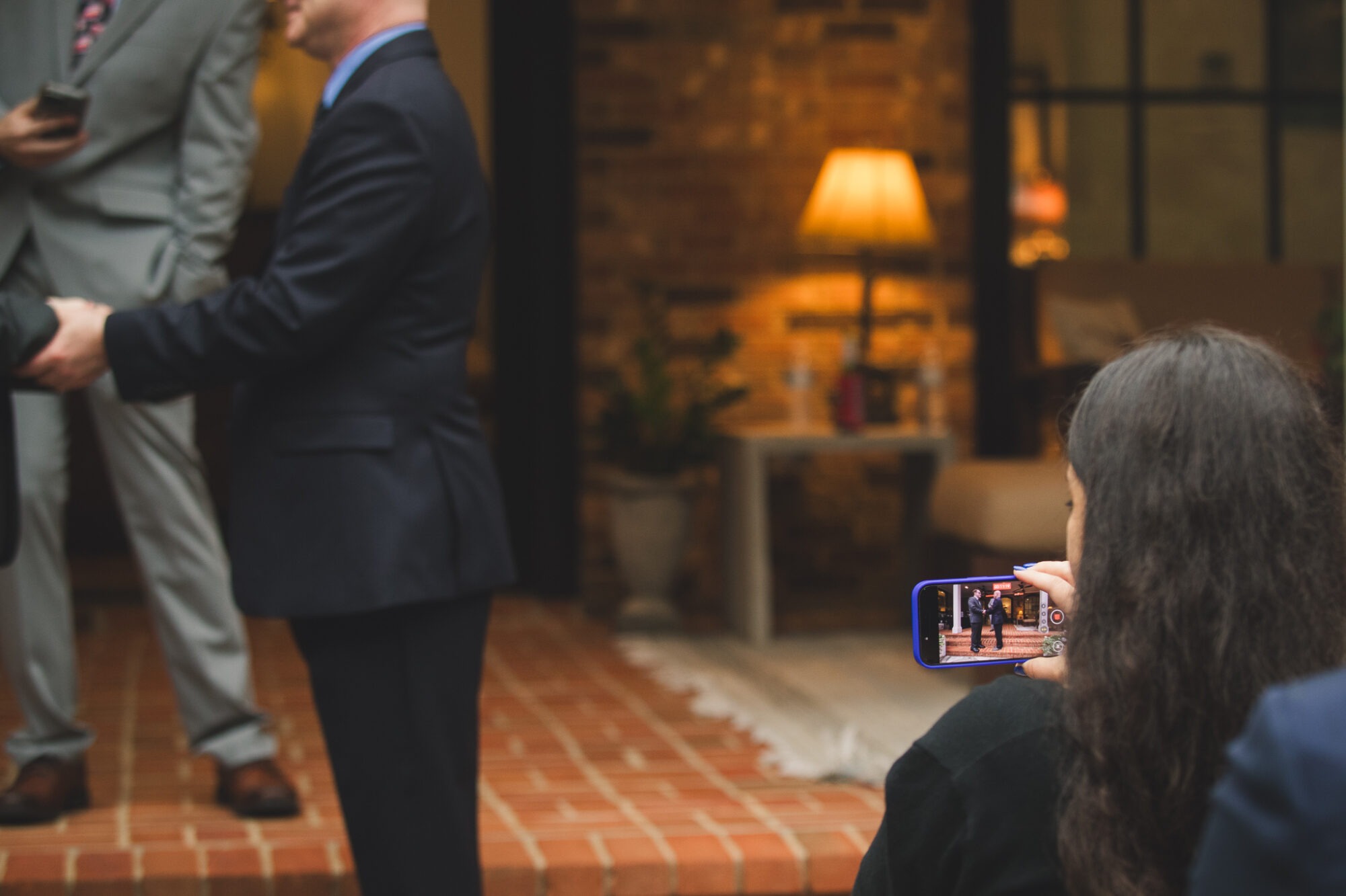 Wedding guest holding her cell phone and making a video of the wedding ceremony of two grooms