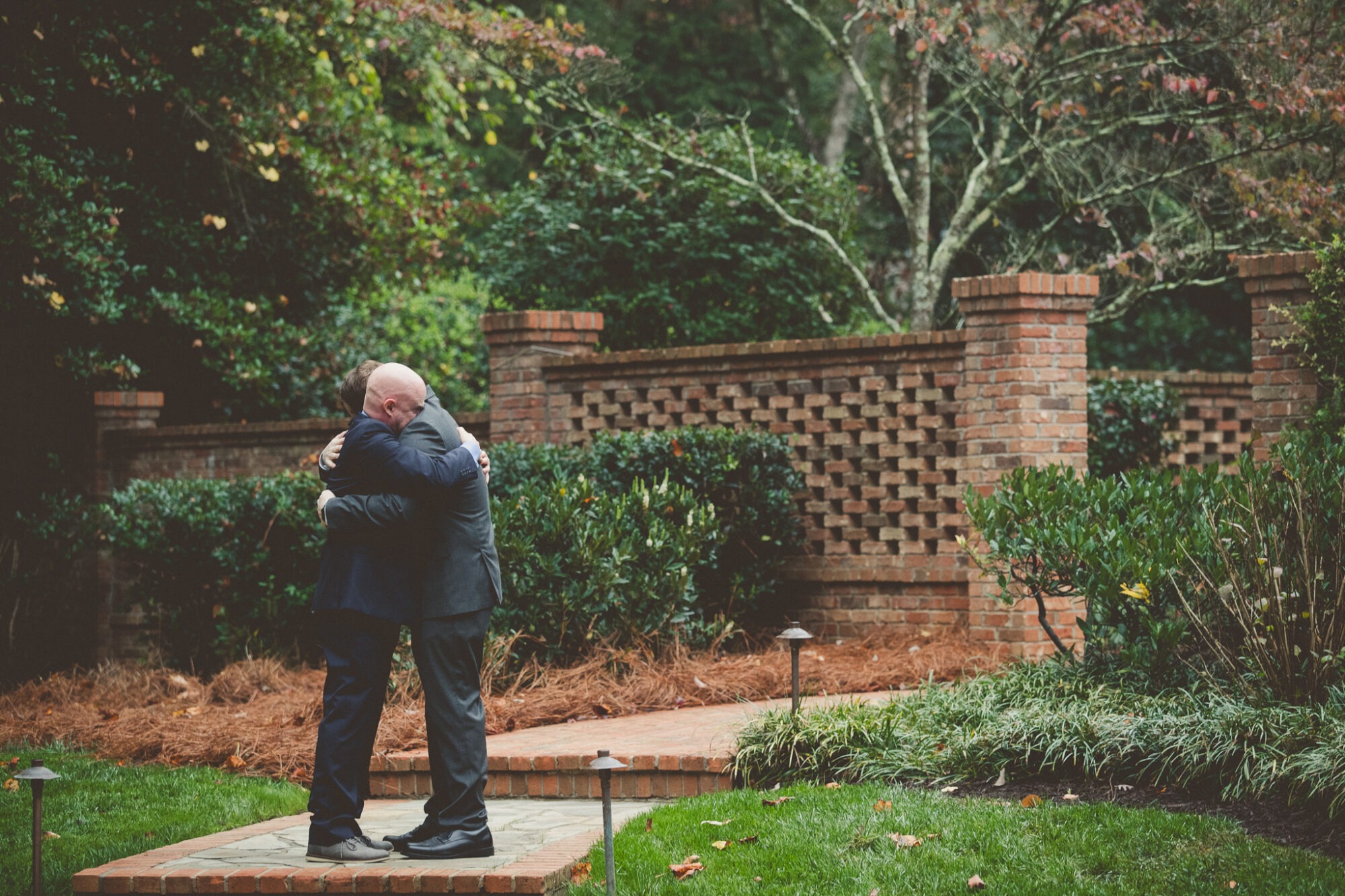 Two grooms hugging each other tight after their backyard Atlanta wedding ceremony