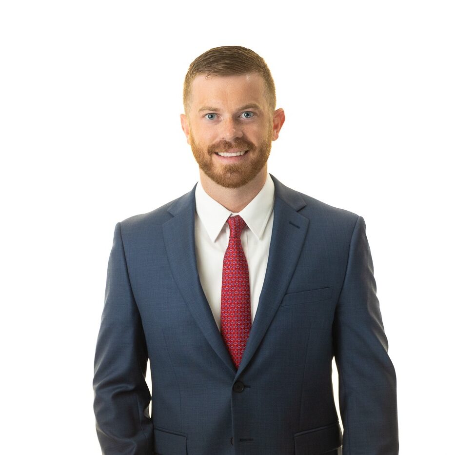 Professional headshot of an Atlanta CPA in a blue suit and red tie. This man is smiling and standing in front of a white background.