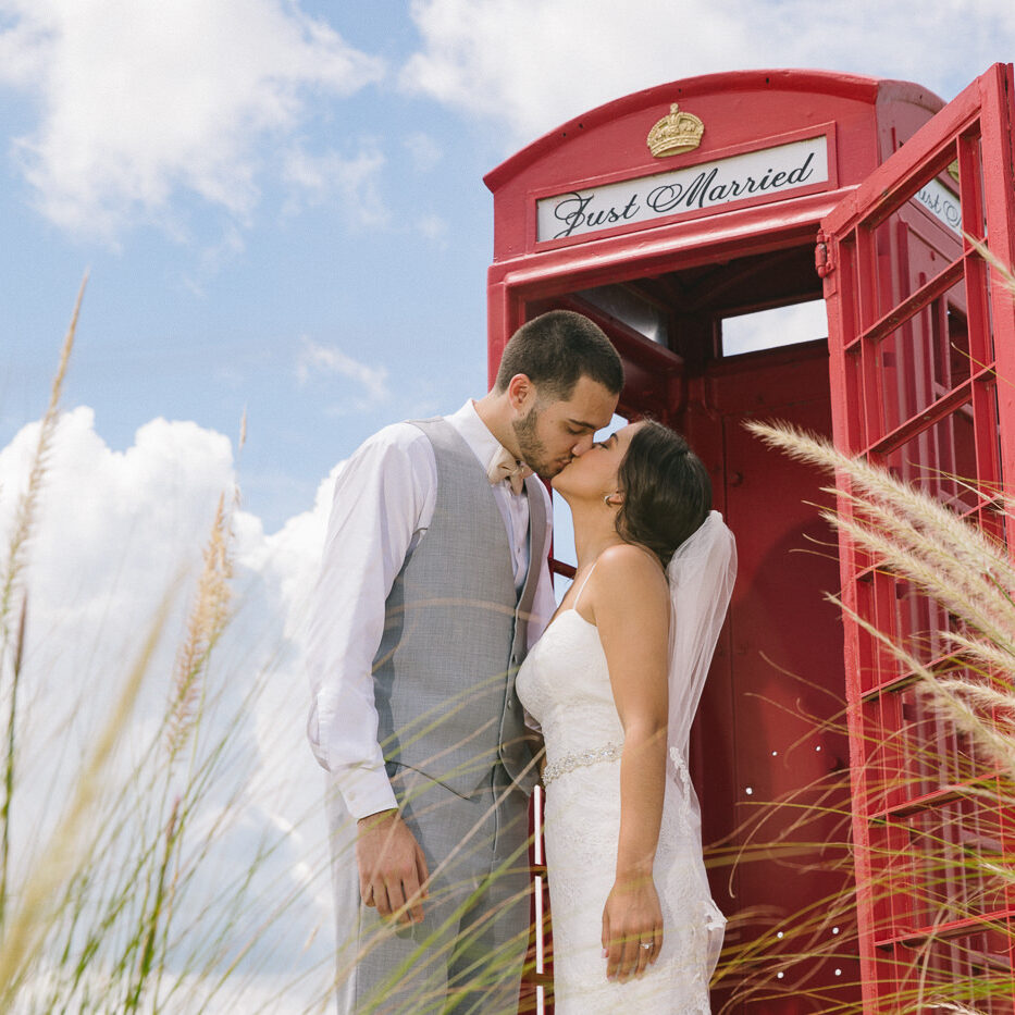 Gorgeous bride + groom kissing in front of Royal Crest Room red phone booth at their destination wedding