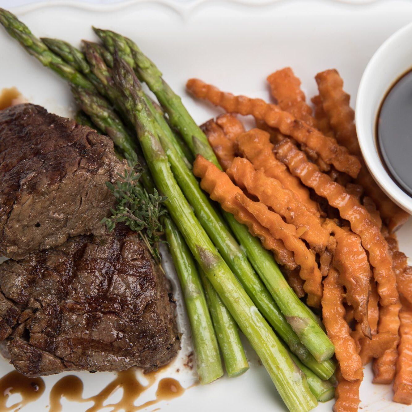 Delicious steak, asparagus, and sweet potato fries plated by Divine Taste of Heaven