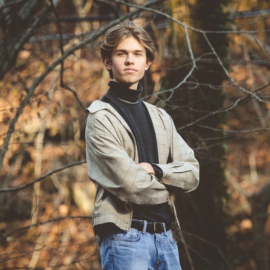 Canton high school senior boy standing with his arms cross wearing a jacket and jeans