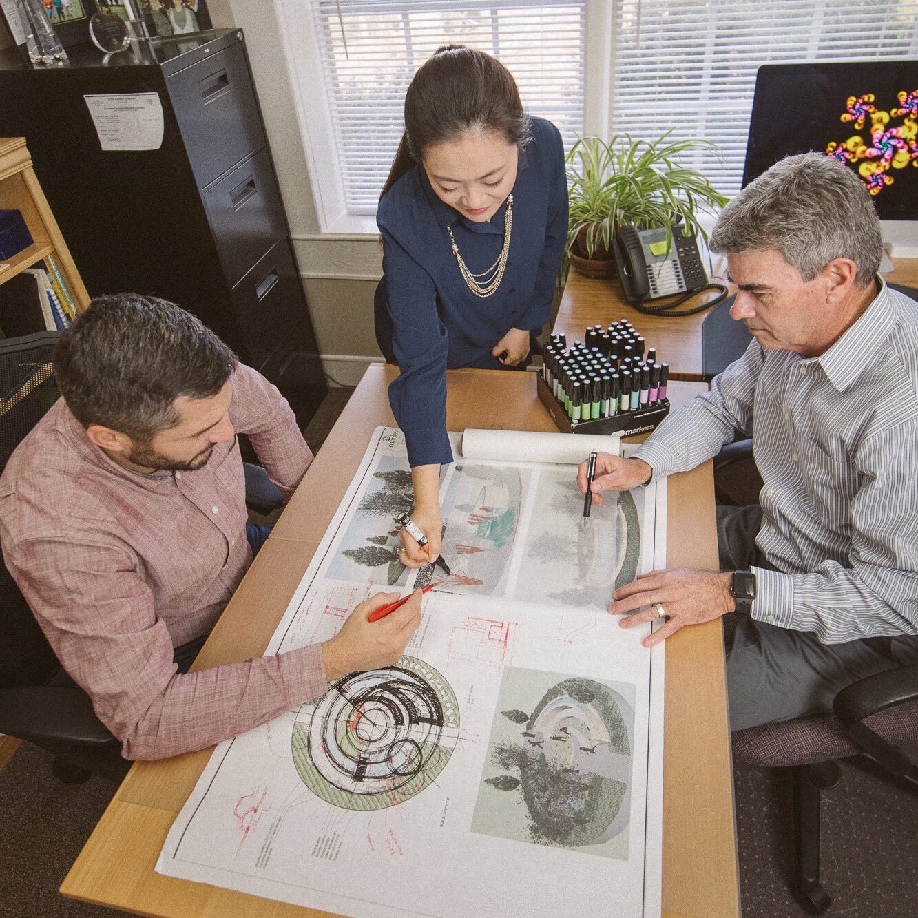 Three landscaping architects working on blueprints together at Manley Land Design office