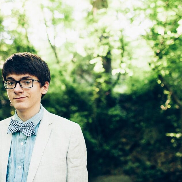 High school senior boy in woods with glasses and bow tie