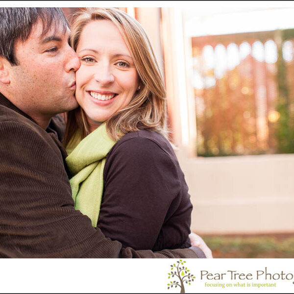 Husband holding his wife tight and smooching her on her cheek at Agness Scott College
