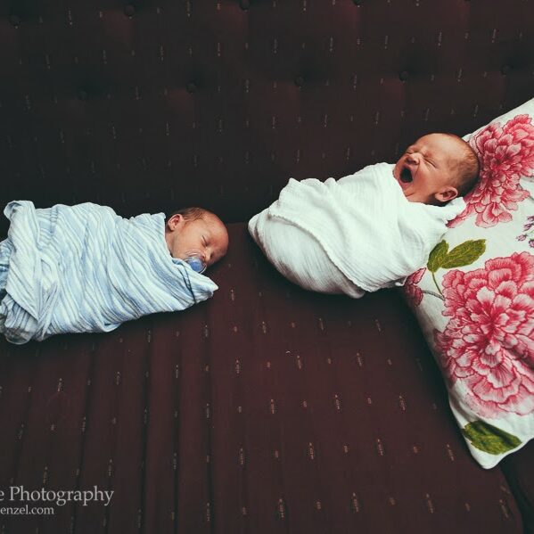 Newborn twins swaddled and lying side-by-side on a sofa
