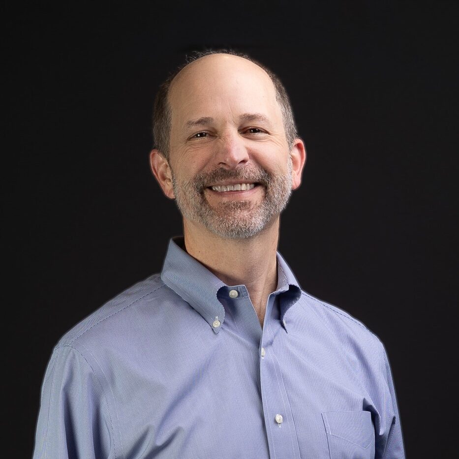 National business coach headshot of Joe Woodard in a blue shirt and dark background