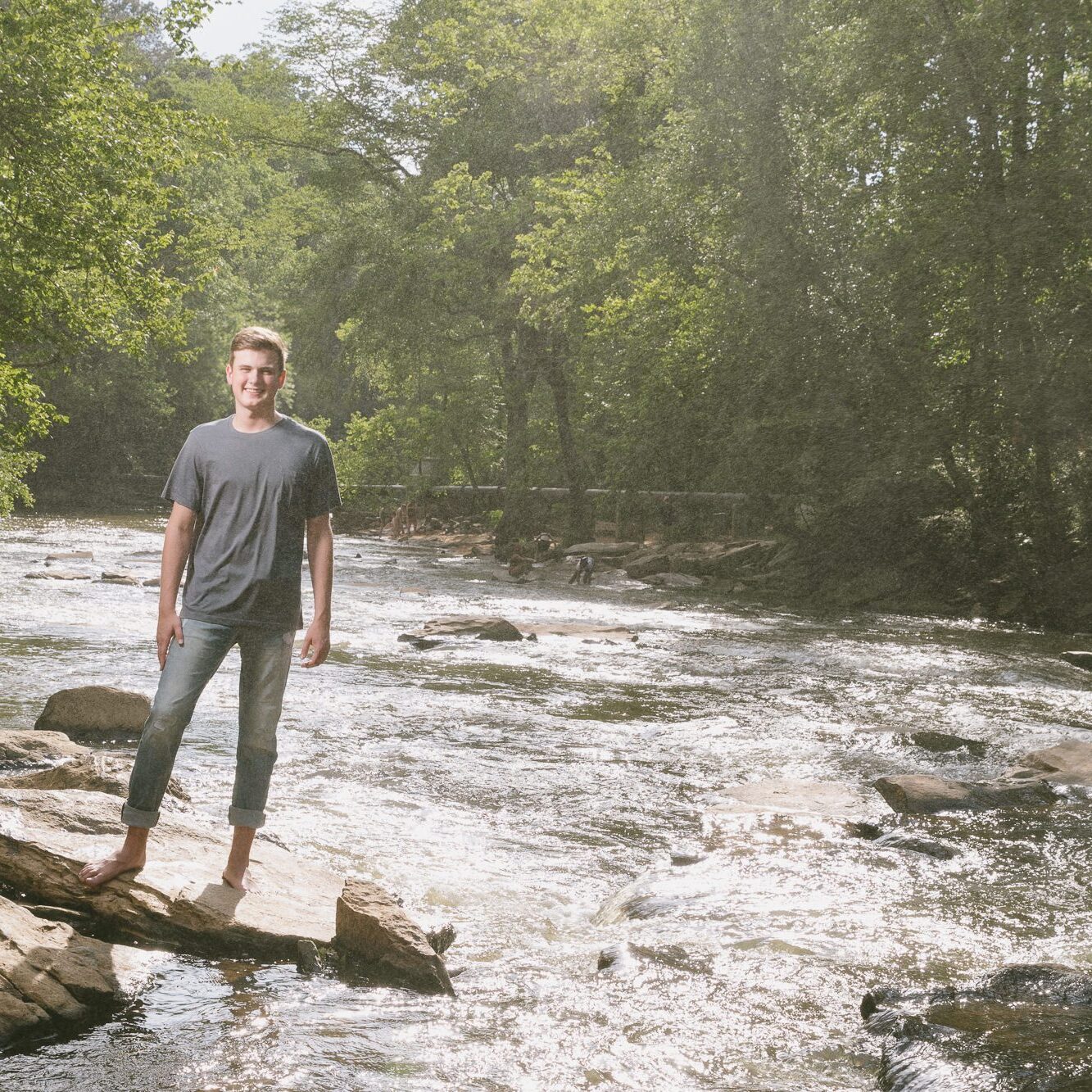 High school senior boy standing on shoals at Vickery Creek near Roswell Mill